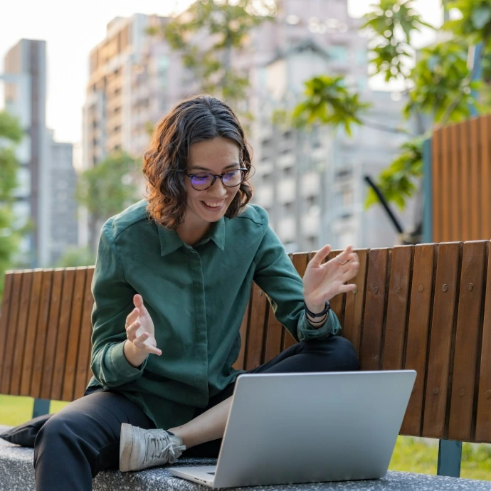 a woman sitting on a bench using a laptop